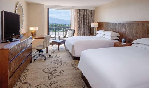 a hotel room with two beds and a flat screen tv at Hilton Waikoloa Village in Waikoloa