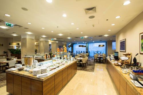 Un restaurante con línea de buffet con mesas y sillas. en Hilton Garden Inn Krakow, en Cracovia