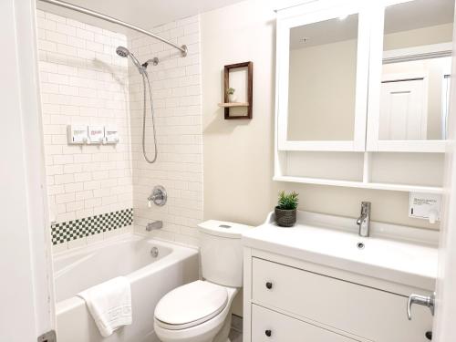 a white bathroom with a toilet and a tub and a sink at Alpenglow Lodge by MVA in Whistler