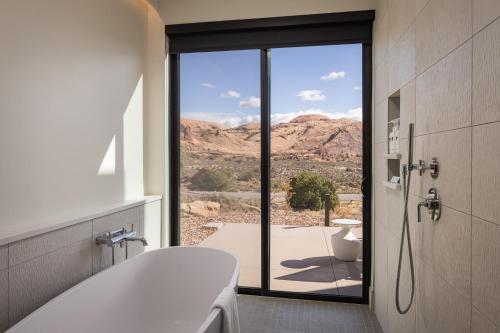 a bathroom with a tub and a view of the desert at LIONSBACK RESORT in Moab
