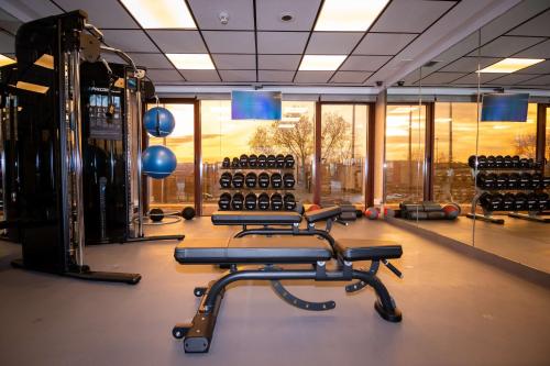 a gym with several rows of exercise equipment and windows at Hilton Madrid Airport in Madrid