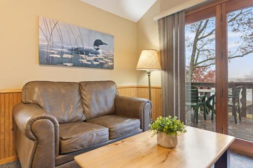 a living room with a leather couch and a table at Cragun's Resort on Gull Lake in Brainerd
