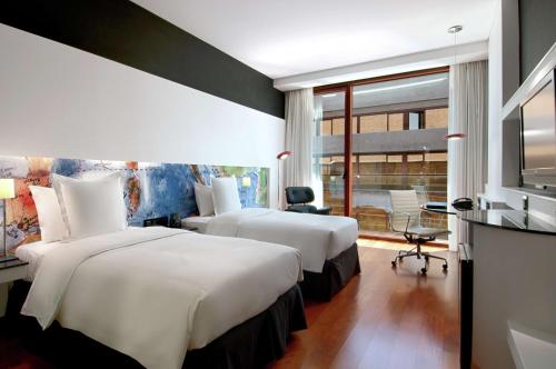 a hotel room with two beds and a desk at Hilton Madrid Airport in Madrid