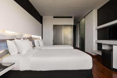 a bedroom with a large white bed and a tv at Hilton Madrid Airport in Madrid