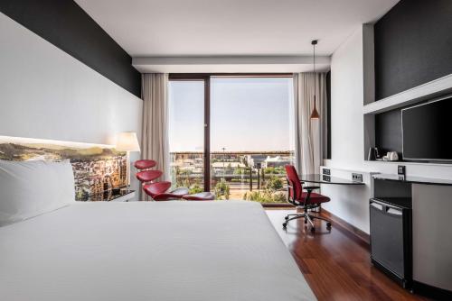 a hotel room with a bed and a large window at Hilton Madrid Airport in Madrid