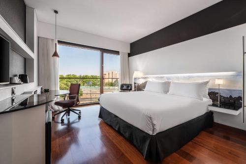 a hotel room with a large bed and a desk at Hilton Madrid Airport in Madrid