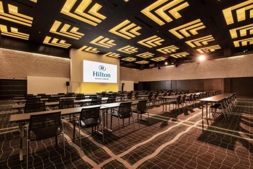 a lecture hall with tables and chairs and a screen at Hilton Madrid Airport in Madrid