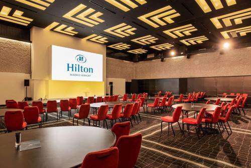 a conference room with tables and red chairs at Hilton Madrid Airport in Madrid