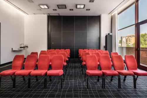a conference room with red chairs and a screen at Hilton Madrid Airport in Madrid