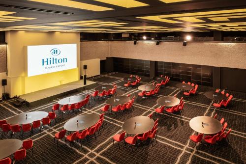 a room with tables and red chairs and a screen at Hilton Madrid Airport in Madrid