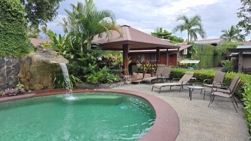 a swimming pool with a fountain in a yard at Hotel Iris Arenal in Fortuna