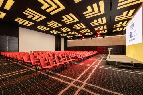 a lecture hall with red chairs and a stage at Hilton Madrid Airport in Madrid