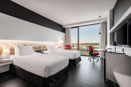 a hotel room with two beds and a television at Hilton Madrid Airport in Madrid