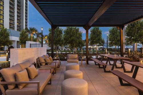 a patio with tables and chairs and tables and benches at Embassy Suites by Hilton Myrtle Beach Oceanfront Resort in Myrtle Beach