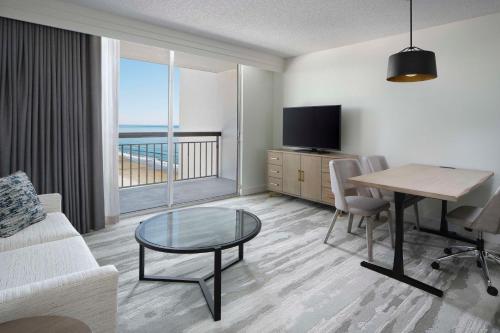 a living room with a couch and a table and a television at Embassy Suites by Hilton Myrtle Beach Oceanfront Resort in Myrtle Beach
