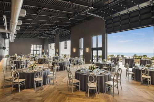 a banquet hall with tables and chairs in a room with large windows at Embassy Suites by Hilton Myrtle Beach Oceanfront Resort in Myrtle Beach