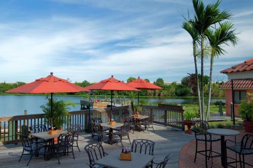 a patio with tables and chairs and a lake at Hilton Palm Beach PBI in West Palm Beach
