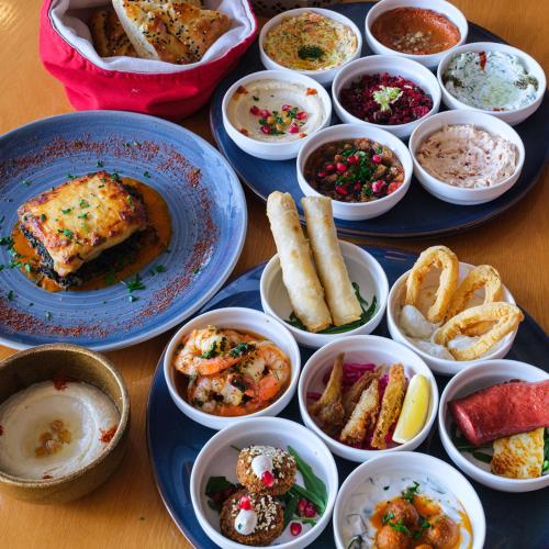 a table with plates of food and bowls of food at DoubleTree by Hilton Resort & Spa Marjan Island in Ras al Khaimah