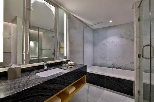 a bathroom with a tub and a sink and a shower at DoubleTree by Hilton Resort & Spa Marjan Island in Ras al Khaimah