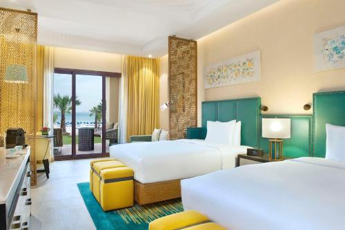 a hotel room with two beds and a balcony at DoubleTree by Hilton Resort & Spa Marjan Island in Ras al Khaimah