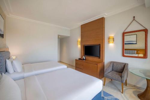 a white bedroom with a bed and a chair and a sink at DoubleTree by Hilton Resort & Spa Marjan Island in Ras al Khaimah