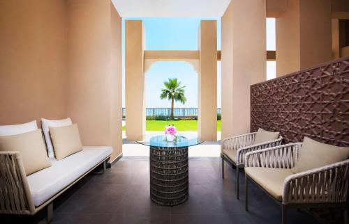 a patio with chairs and a table and a palm tree at DoubleTree by Hilton Resort & Spa Marjan Island in Ras al Khaimah