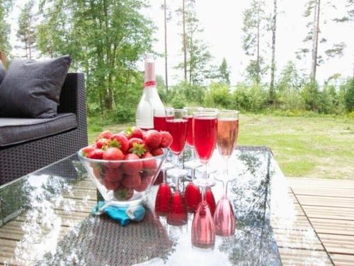 a glass table with glasses of wine and a bowl of fruit at Koivuniemen Tila II in Säkylä