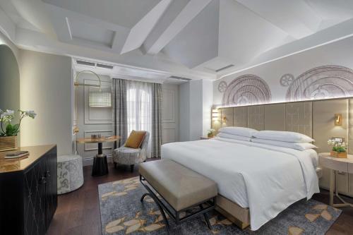 a bedroom with a large white bed and a desk at Hilton Molino Stucky Venice in Venice
