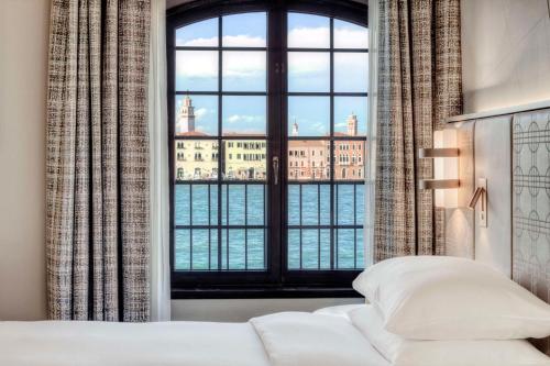 a bedroom with a large window overlooking the water at Hilton Molino Stucky Venice in Venice