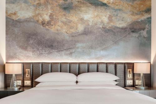 a bedroom with a bed with a painting above it at Hilton Molino Stucky Venice in Venice