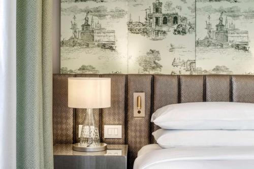 a bedroom with a bed and a table with a lamp at Hilton Molino Stucky Venice in Venice