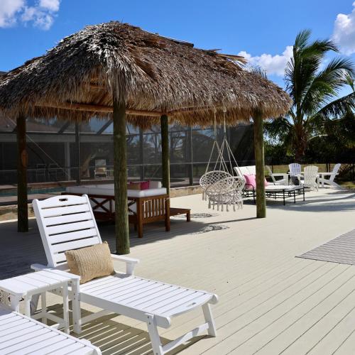 a deck with chairs and a straw umbrella and tables at Dreamers Hideaway I Waterfront I Direct Access in Naples