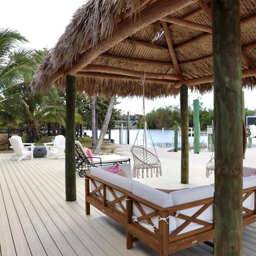 a wooden deck with a hammock and a straw umbrella at Dreamers Hideaway I Waterfront I Direct Access in Naples