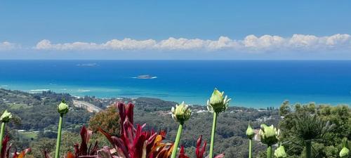 a view of the ocean and flowers on a mountain at ON TOP Of THE WORLD Garden Studio in Kororo Basin