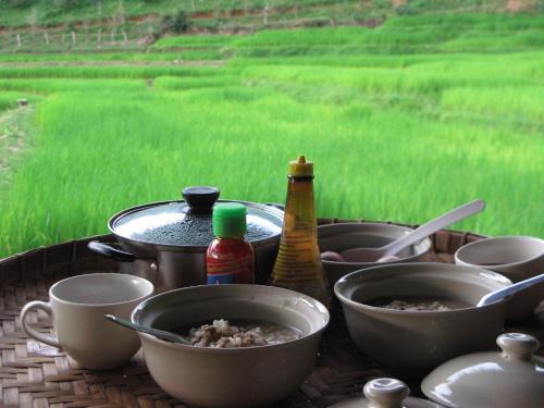 a table with bowls of food and a view of a field at Chibacall ชิบะคอล, Karen Mountain Hideaway Homestay in Ban Pha Mon