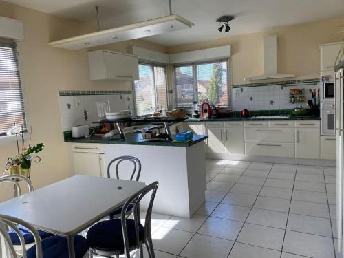 une cuisine avec des armoires blanches et une table et des chaises dans l'établissement Chez Spirou 20 mn Disney 20mn Paris, à Noisy-le-Grand