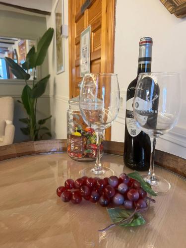 two wine glasses and a bunch of grapes on a table at Casa Flor, Encanto en La Rioja in Lardero