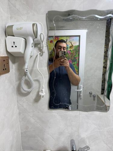 a man taking a picture of himself in a bathroom mirror at Sarko hotel فندق سركو in Baghdad