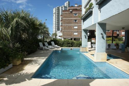 a swimming pool with chairs and a building at Jamaica Punta del Este Hotel & Residence in Punta del Este