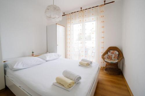een slaapkamer met een wit bed met handdoeken erop bij Apartments Petri in Tisno