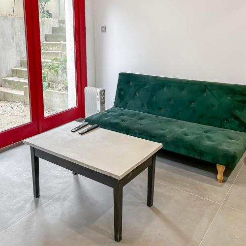 - un salon avec un canapé vert et une table basse dans l'établissement Maison Atypique accès direct Paris, Cuisine design, à Bois-Colombes
