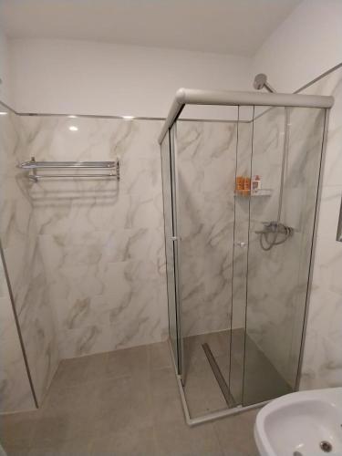 a shower with a glass door next to a sink at Prado del Lago in Villa Rumipal