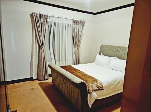 a bedroom with a bed and a window with curtains at Cozy Two Bedroom Oasis In The Heart Of Fourways Sandton in Trevallyn