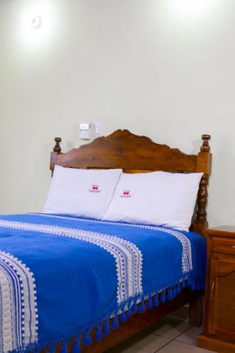 a bed with a blue blanket and white pillows at Hotel Magda in Oaxaca City