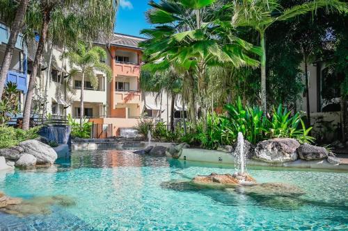 a fountain in the middle of a pool with palm trees at La Palma Cairns- Resort 9 Pools & Gym in Westcourt