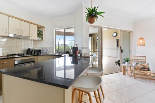 a kitchen with a black counter top and some chairs at La Palma Cairns- Resort 9 Pools & Gym in Westcourt