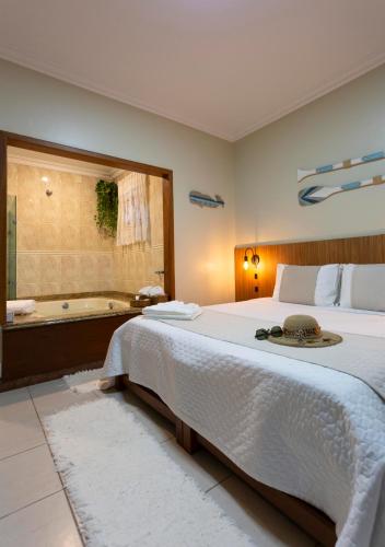 a bedroom with a large bed and a bath tub at Pousada Timoneiro in Vila Velha