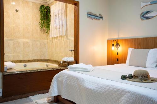 a bedroom with a bed and a bath tub at Pousada Timoneiro in Vila Velha