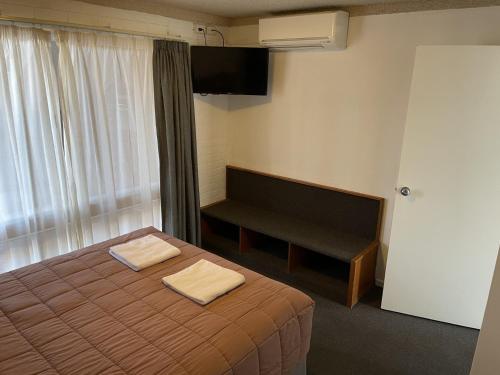 a hotel room with a bed with two towels on it at Homestead Motel in Dubbo