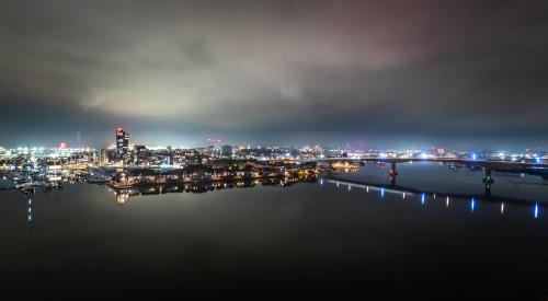 a view of a city at night from the water at The Itchen River Apartments in Southampton